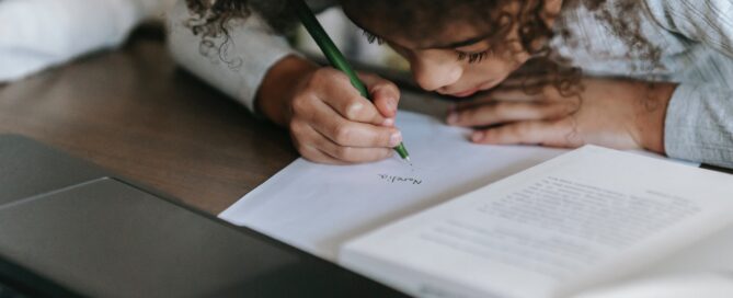 A kid writing on her diary on a desk