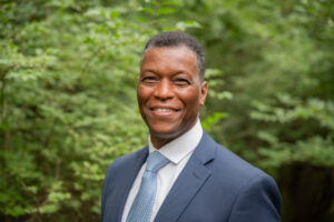 A man standing with trees in the background